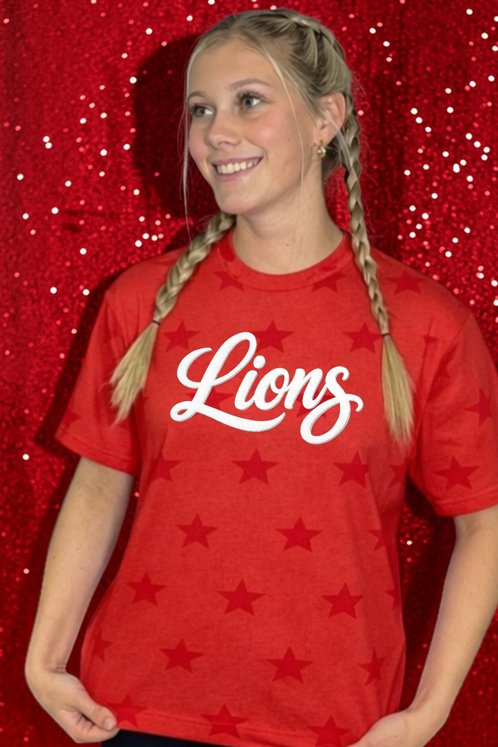 Person wearing a red 'Lions' t-shirt with star patterns against a red glittery background