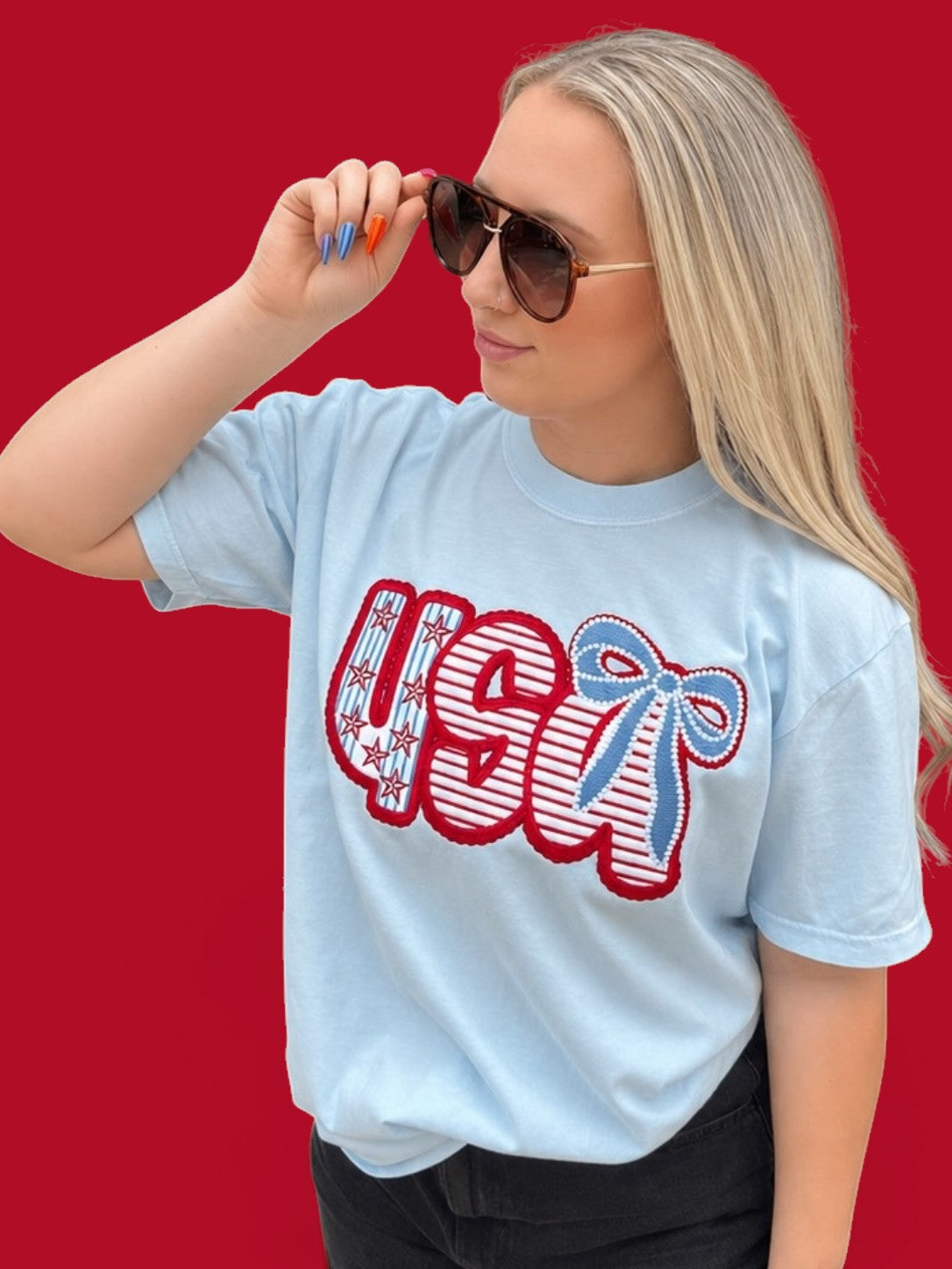 Woman wearing a light blue t-shirt with 'USA' design on a red background