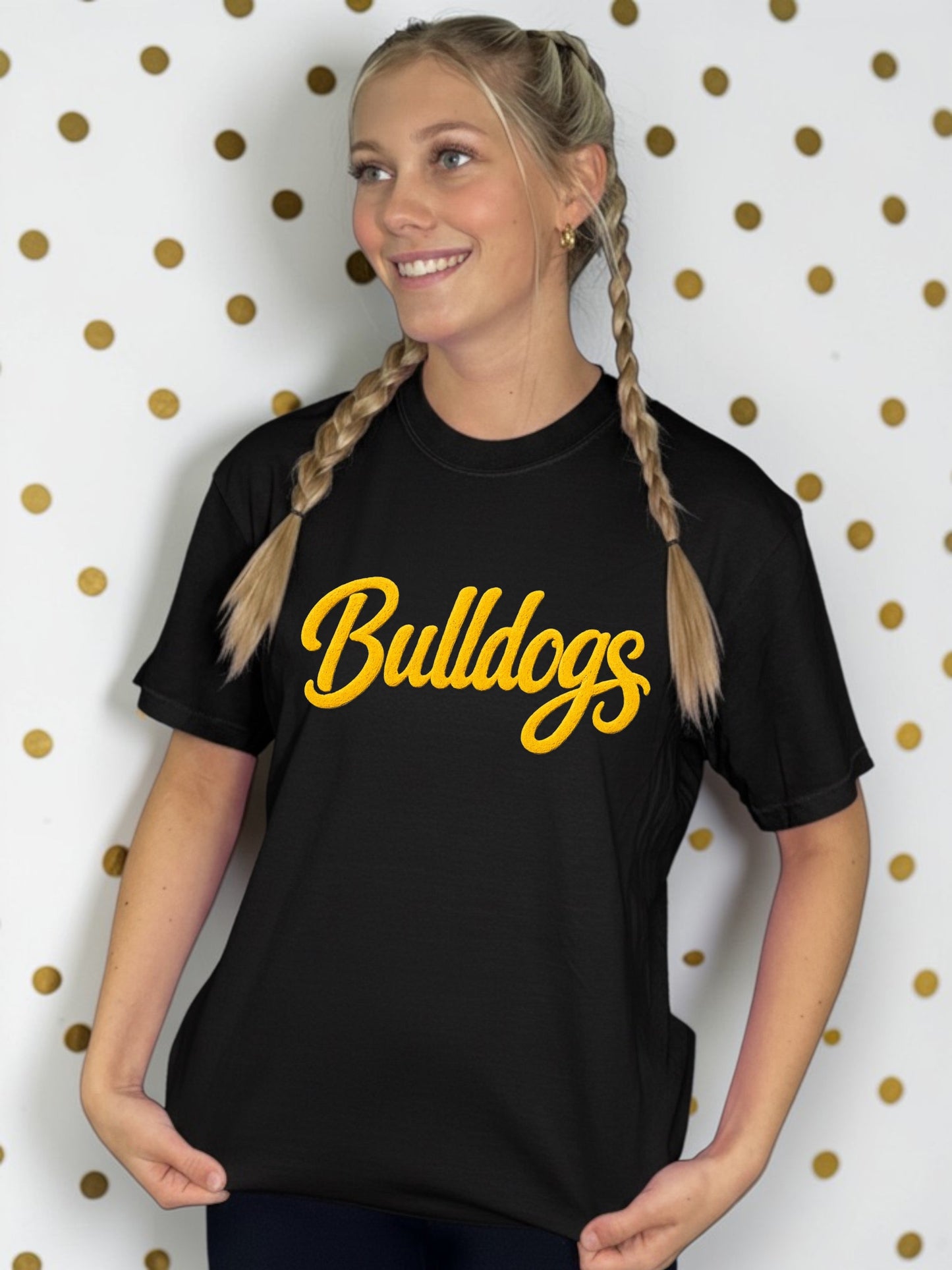 Person wearing a black t-shirt with 'Bulldogs' in yellow text against a polka dot background
