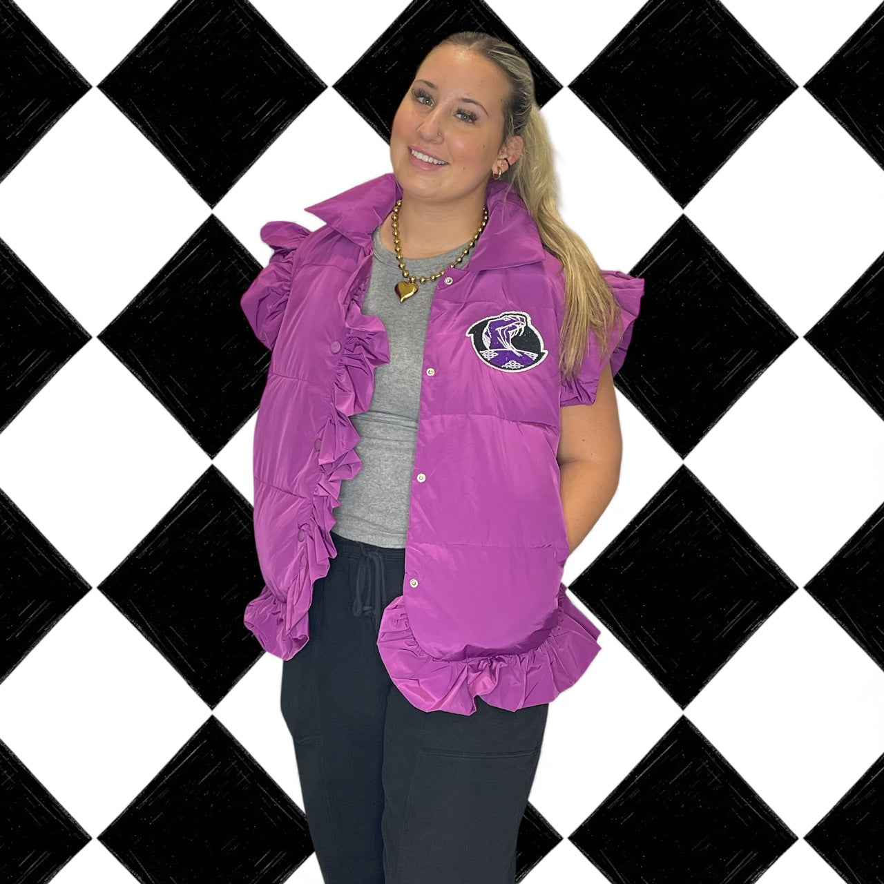 Woman wearing a purple vest with a logo on a black and white checkered background