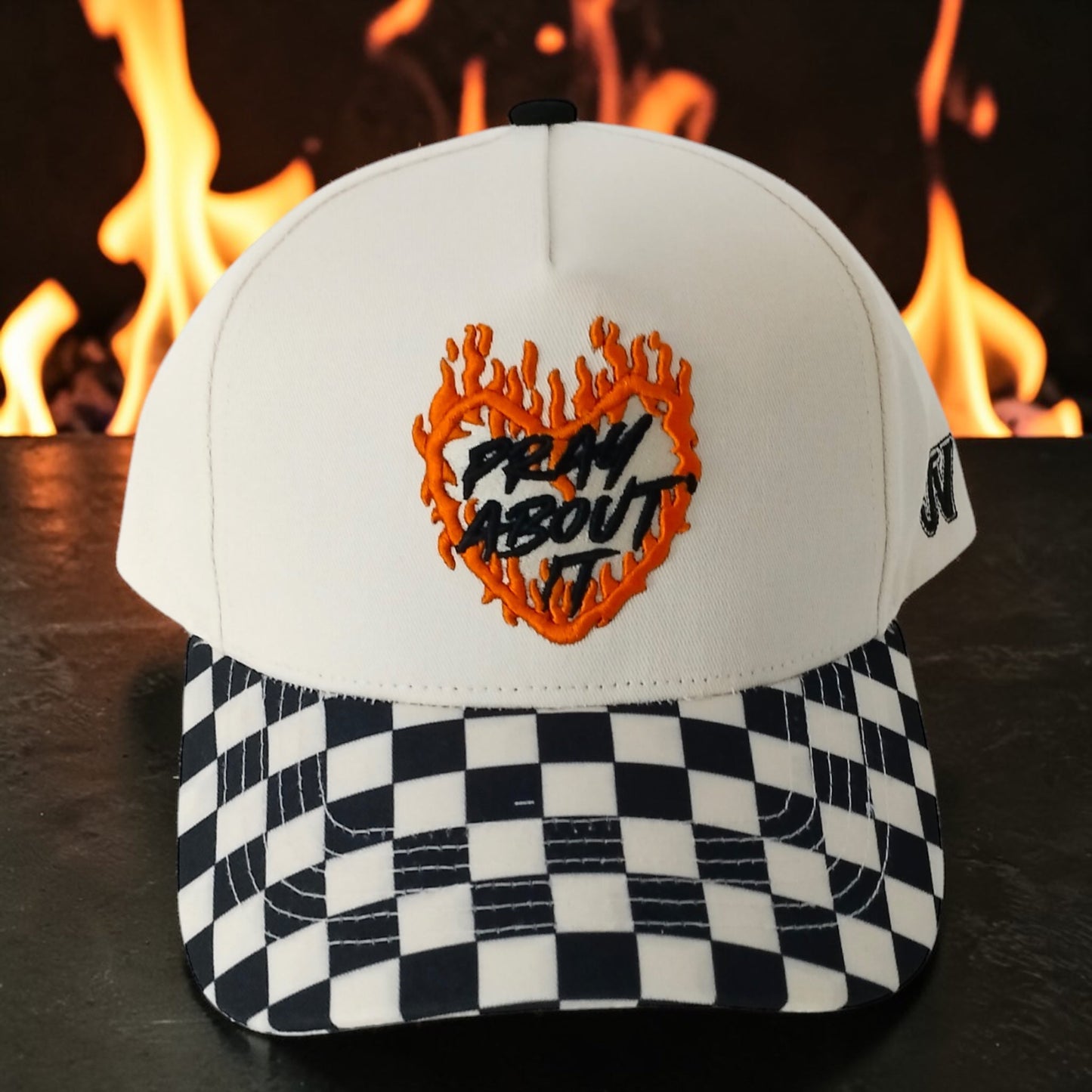 White cap with checkered brim and flame design text against a fiery background