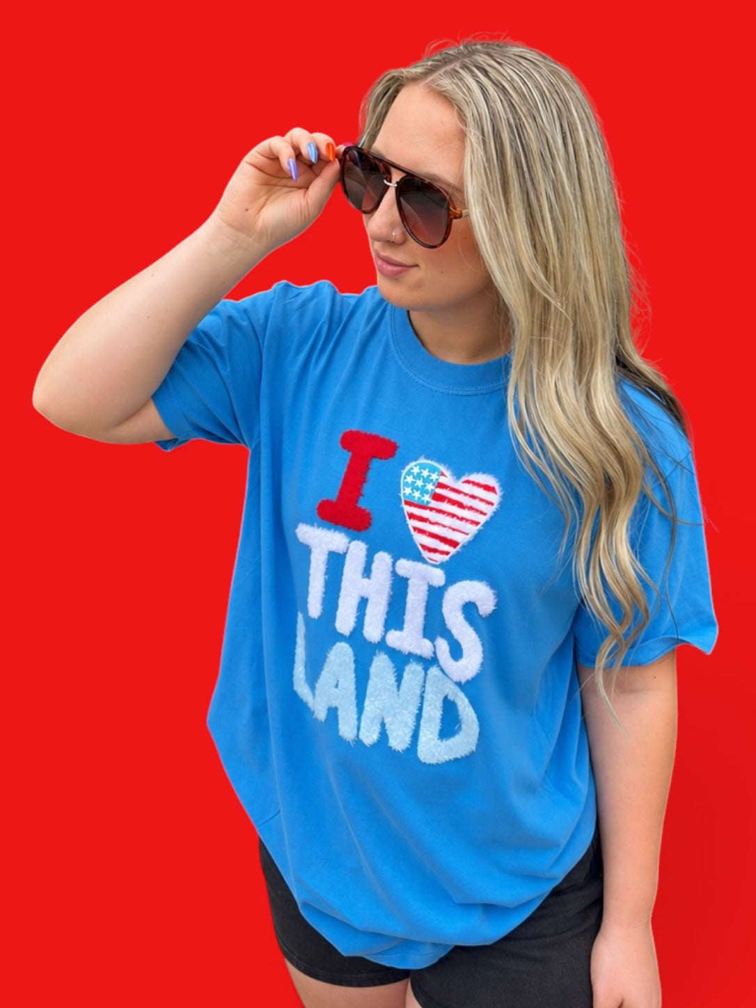 Woman wearing a blue t-shirt with 'I love this land' text on a red background
