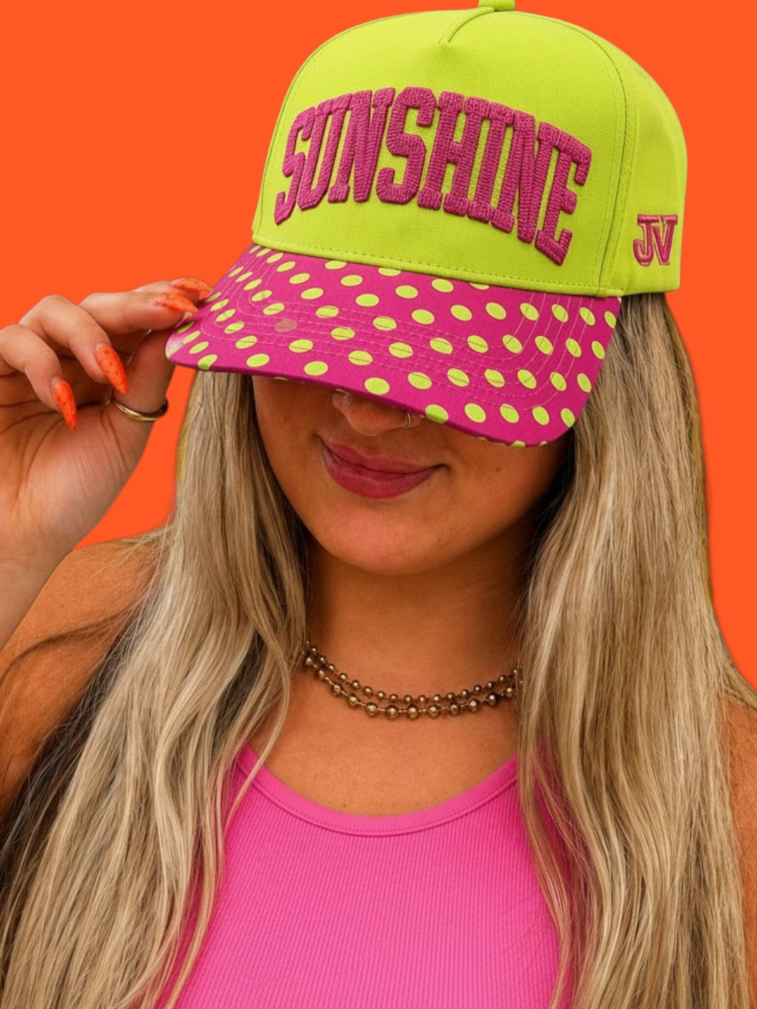 Person wearing a bright green and pink cap with 'SUNSHINE' text on an orange background