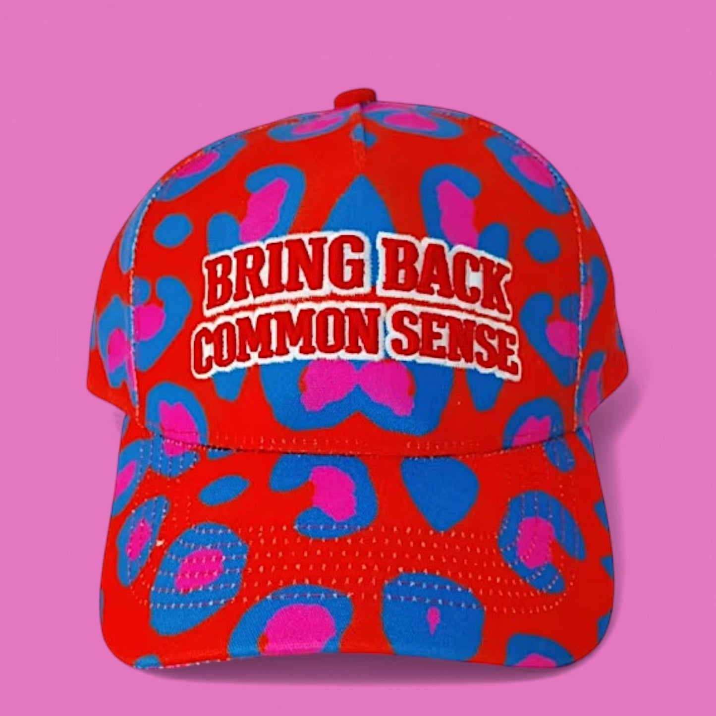 Red cap with blue and pink pattern and 'Bring Back Common Sense' text on a pink background