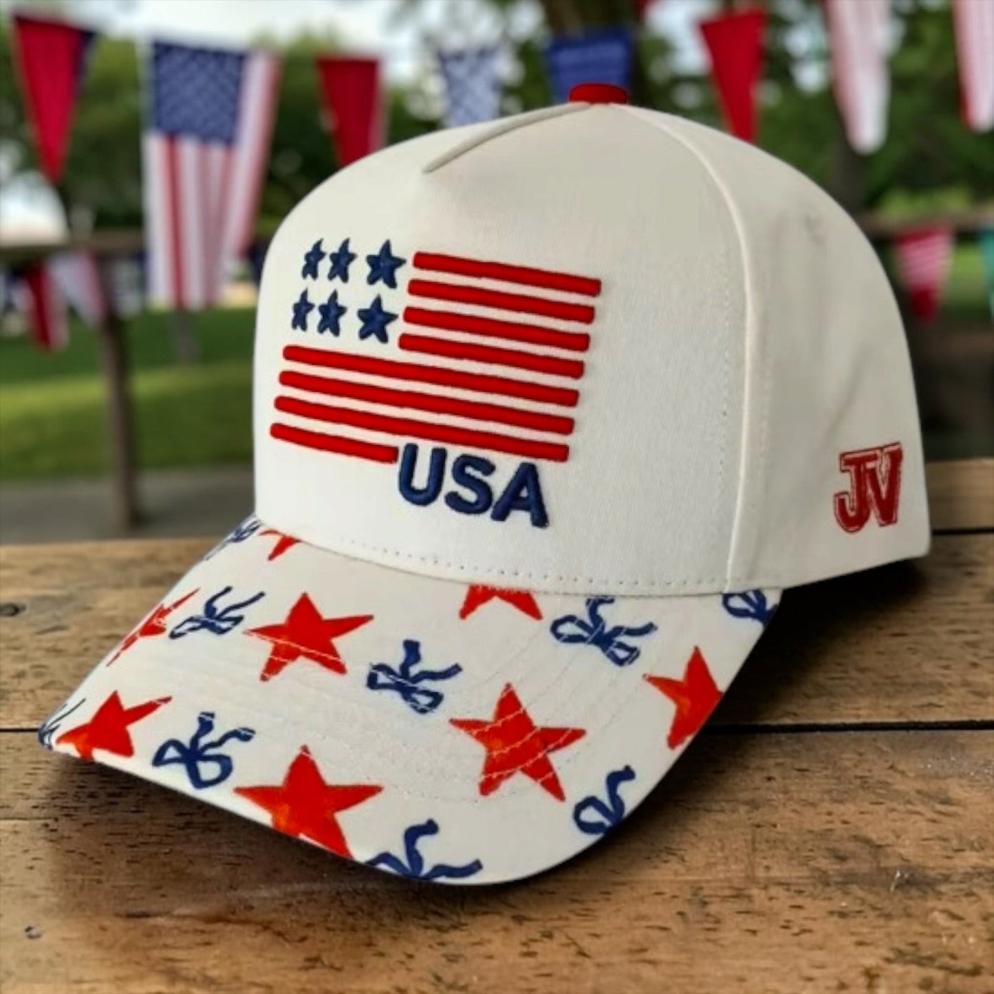 Cap with American flag design and 'USA' text on a wooden surface with blurred flags in the background