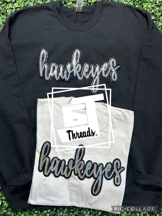 cursive sequin hawkeyes patch on black sweatshirt and white shirt