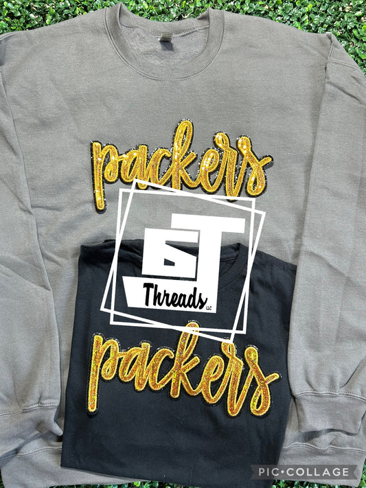 gold cursive sequin packers patch on gray sweatshirt and black shirt