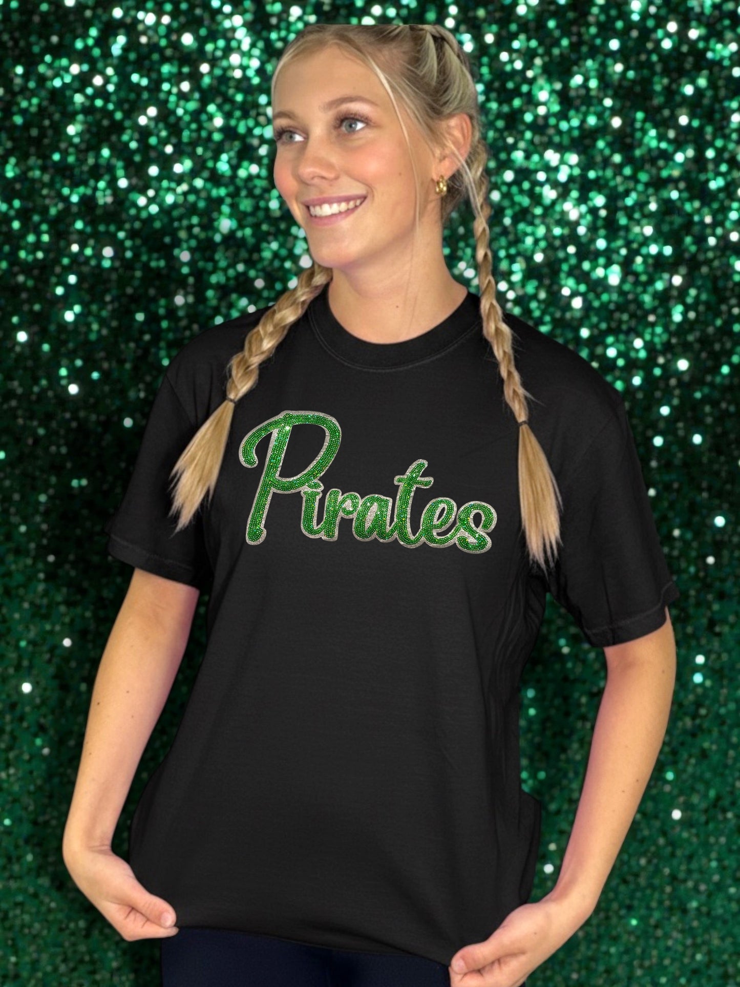 Person wearing a black t-shirt with 'Pirates' printed in green on a glittery green background