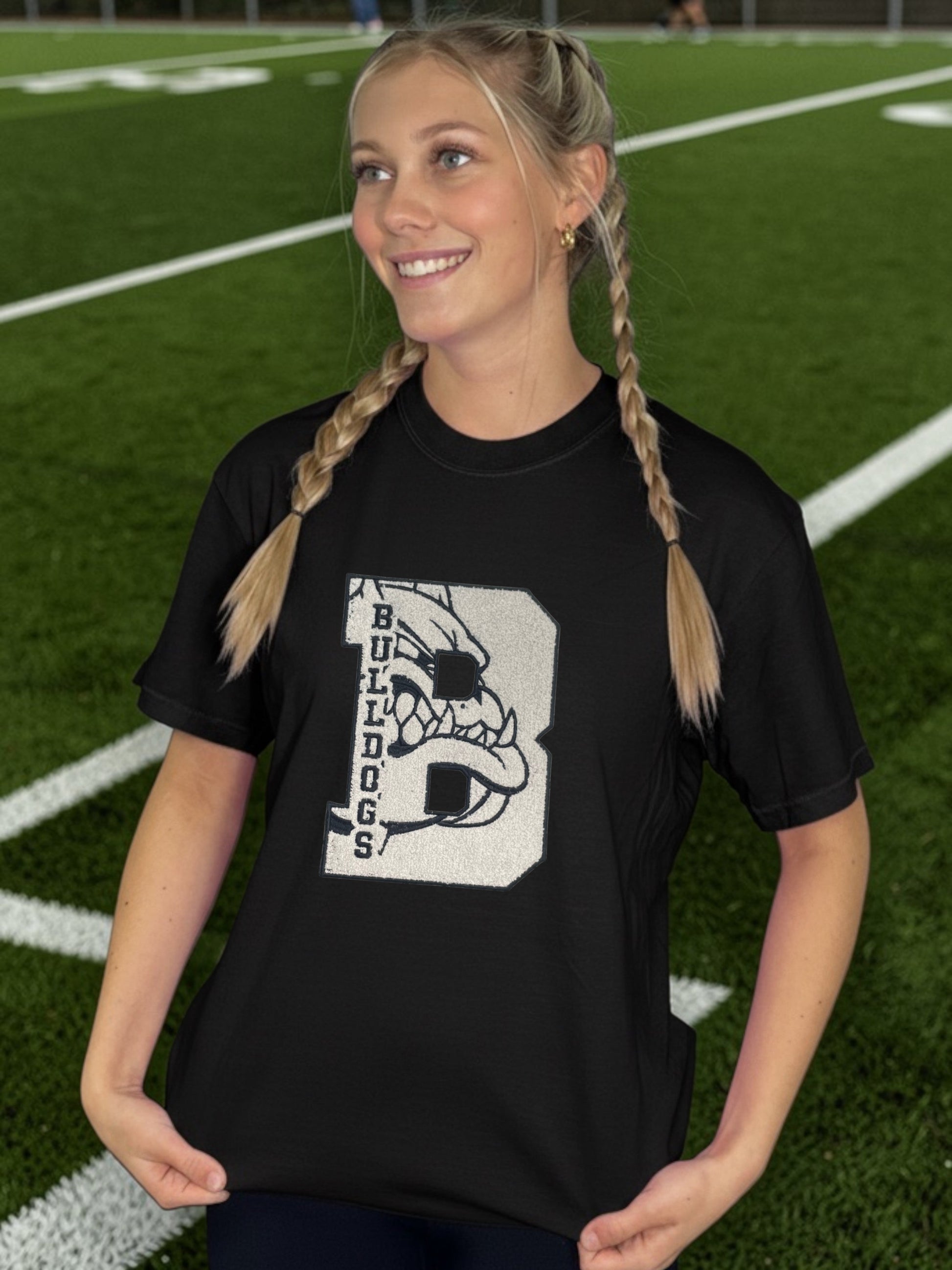 Person wearing a black t-shirt with a bulldog graphic on a sports field