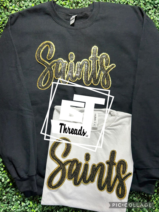 black and gold cursive sequin saints patch on black sweatshirt and white shirt