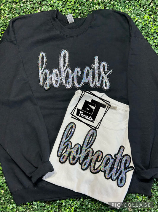 cursive sequin bobcats patch on black sweatshirt and white shirt