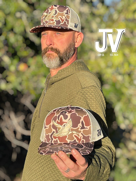 camo duck green hunting flying fishing cap trees in the background tan duck man in green shirt jv cap co 