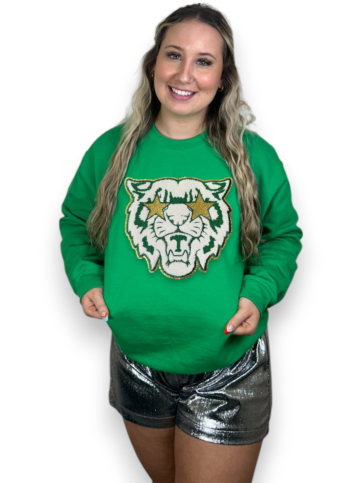 Person wearing a green sweatshirt with a tiger logo on a white background
