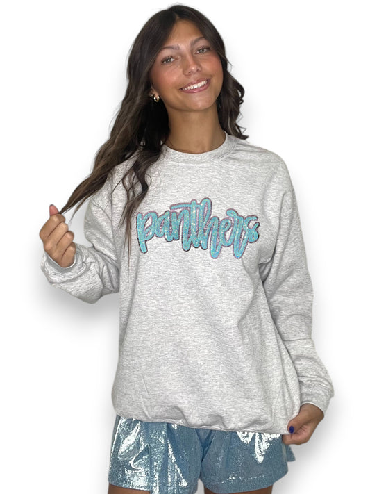 Woman wearing a gray sweatshirt with 'Panthers' text and blue shorts on a white background