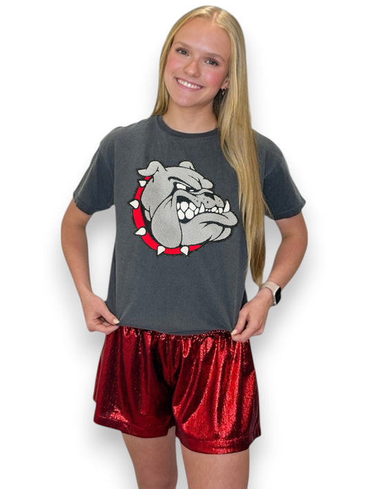 Person wearing a dark gray t-shirt with a bulldog logo and red shorts on a white background