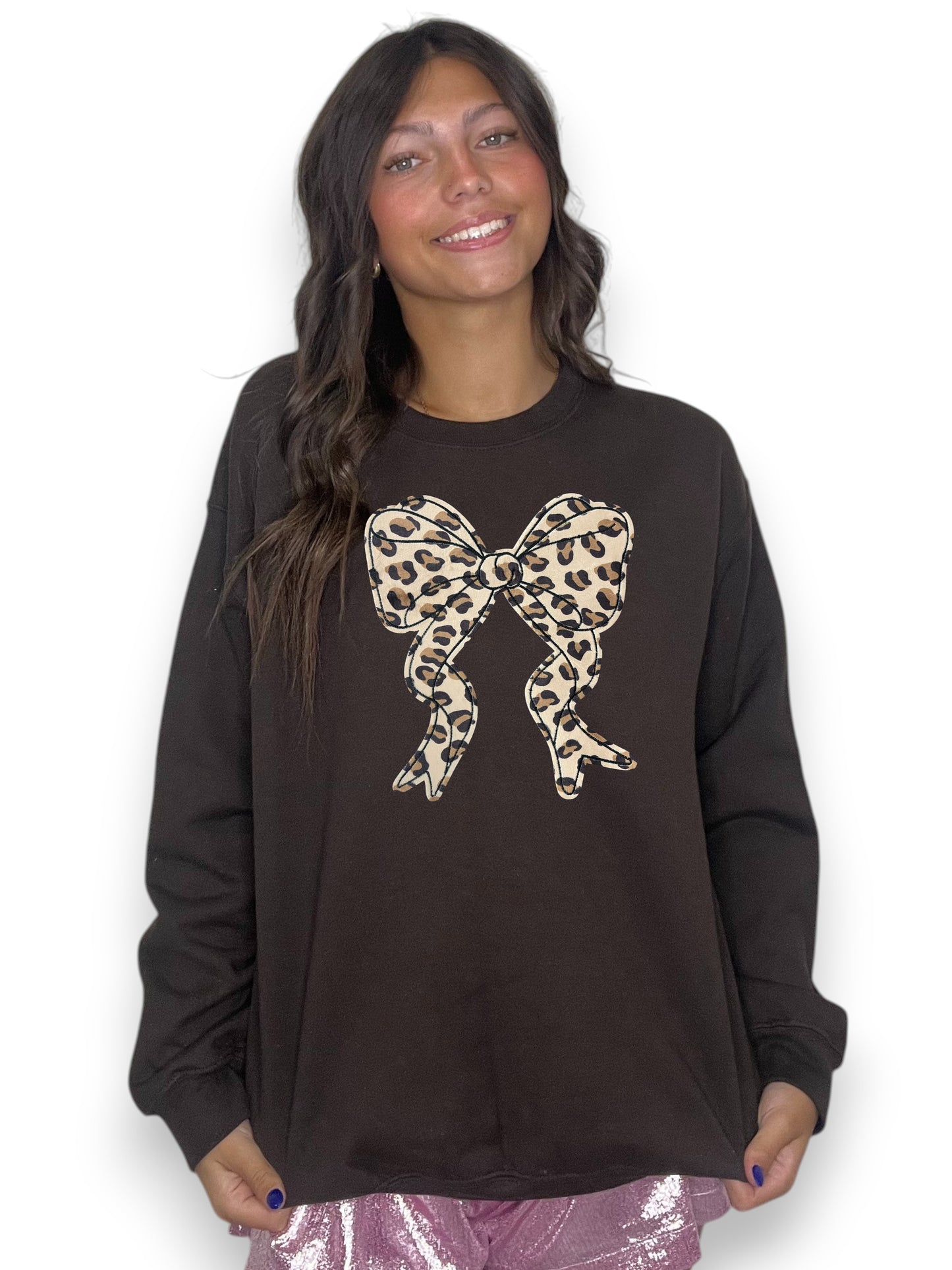 Woman wearing a black sweatshirt with a leopard print bow design on a white background