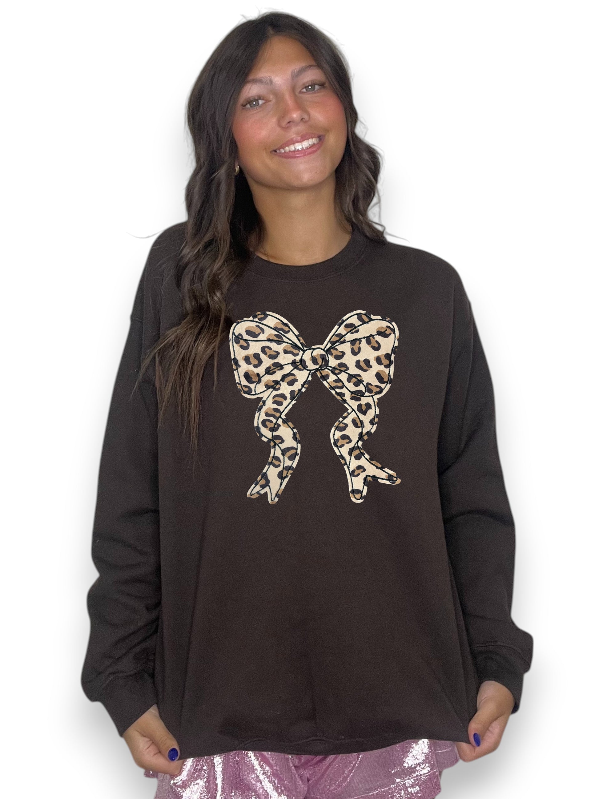 Woman wearing a black sweatshirt with a leopard print bow design on a white background