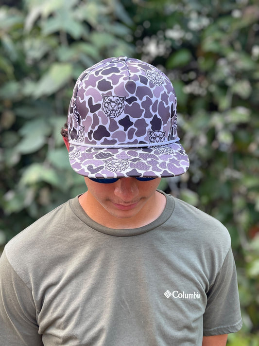 Person wearing a purple camouflage cap with a blurred green background