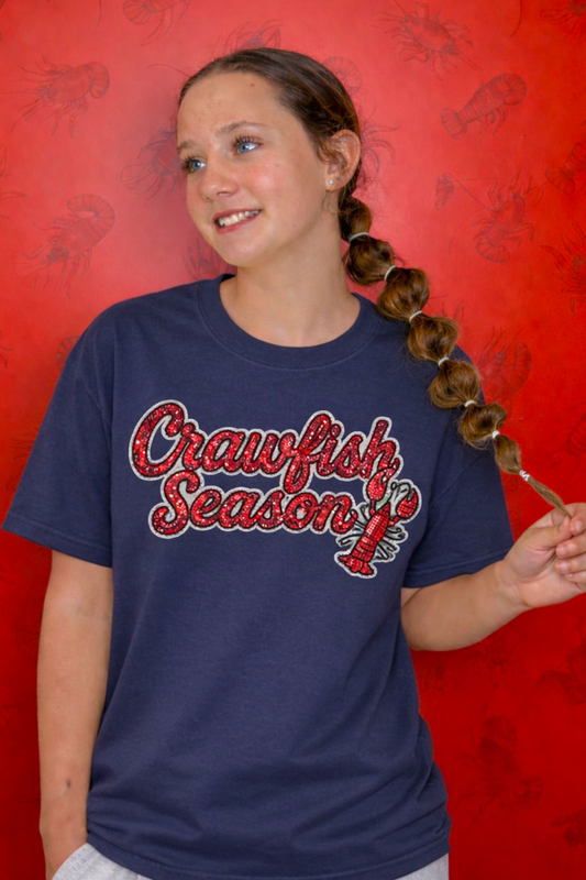 Person wearing a blue t-shirt with 'Crawfish Season' text against a red background