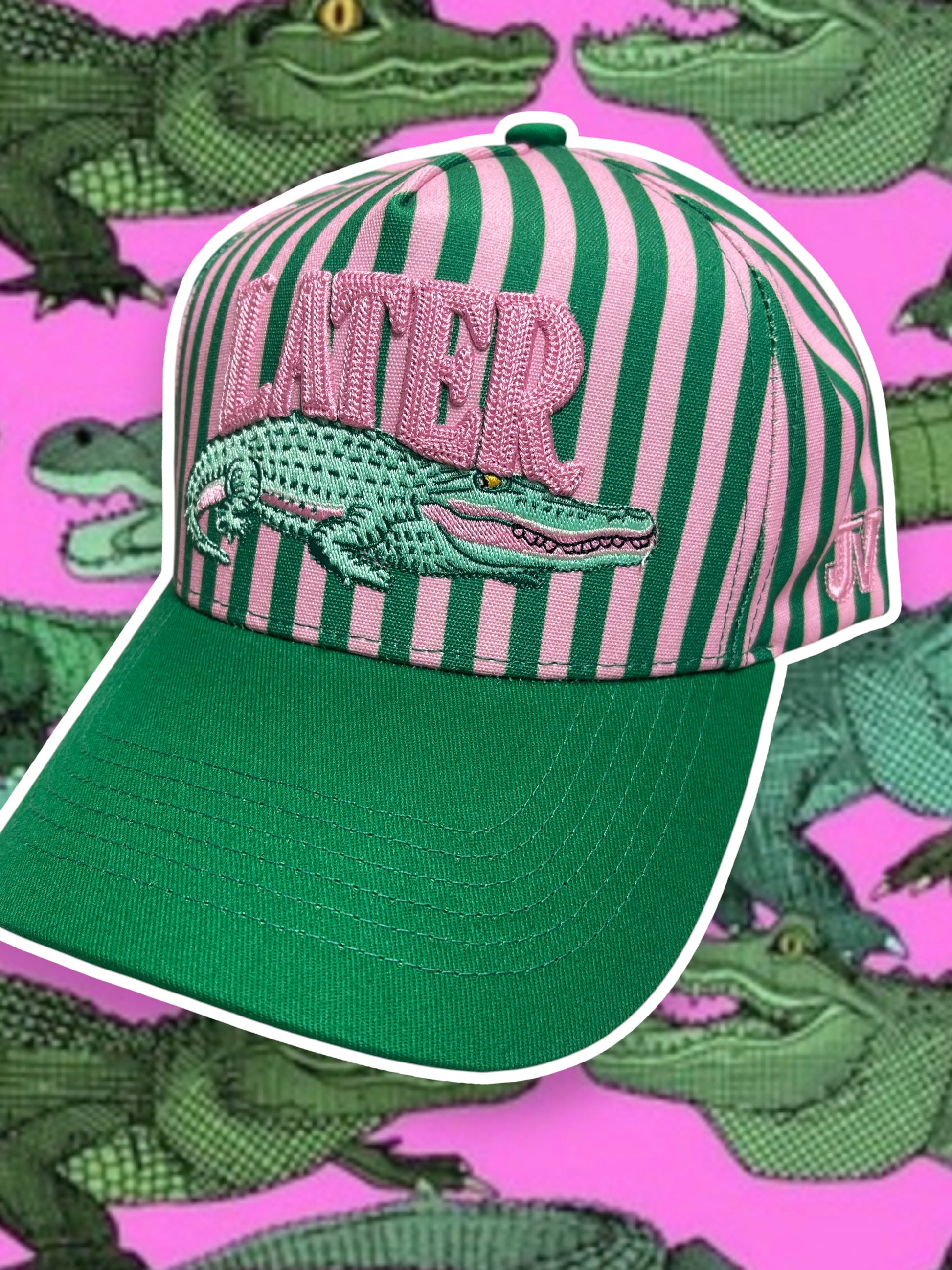 Green and pink striped cap with alligator design and 'LATER' text on a pink background with alligator pattern.