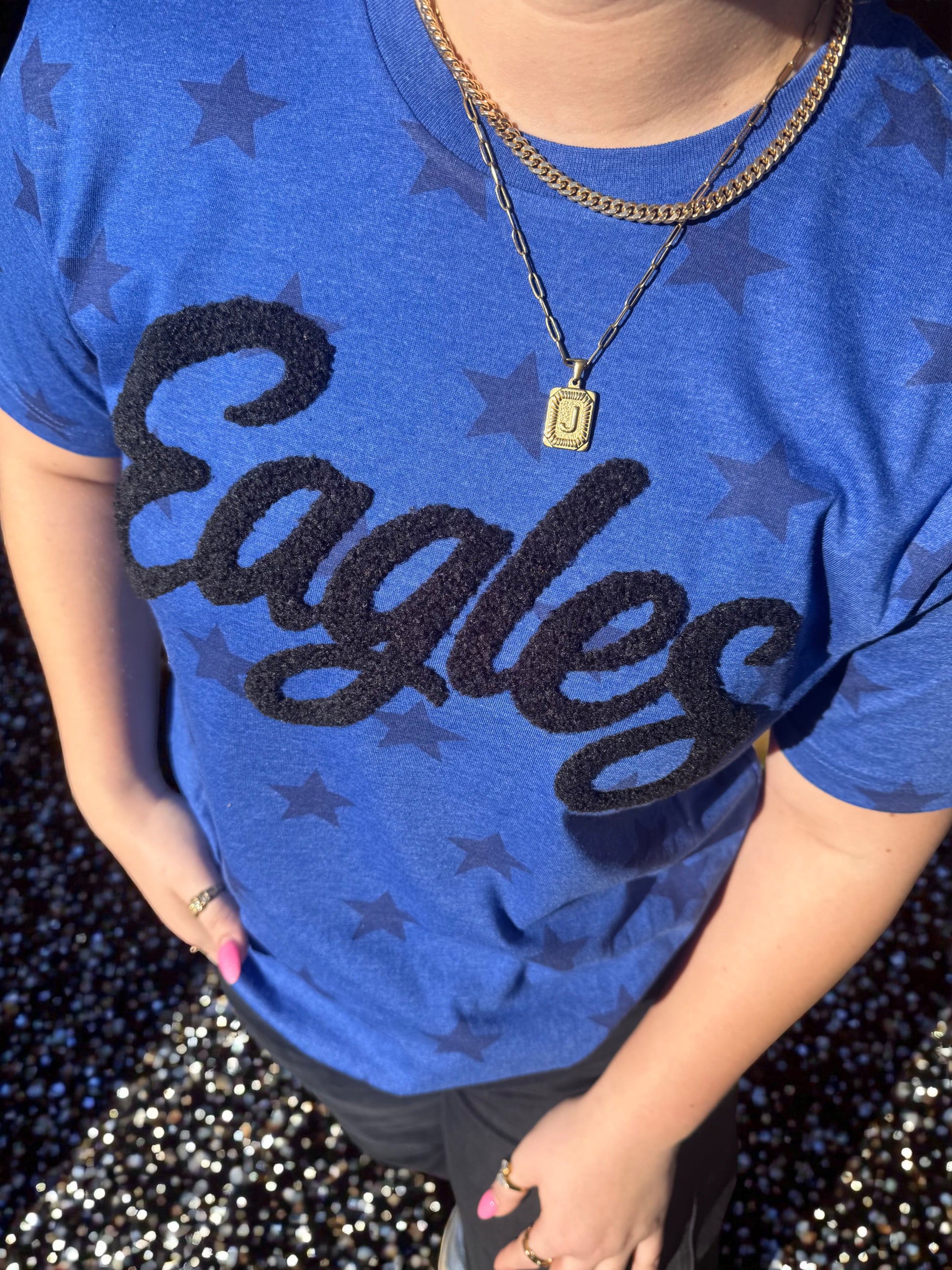 Person wearing a blue 'Eagles' shirt with star patterns on a dark background