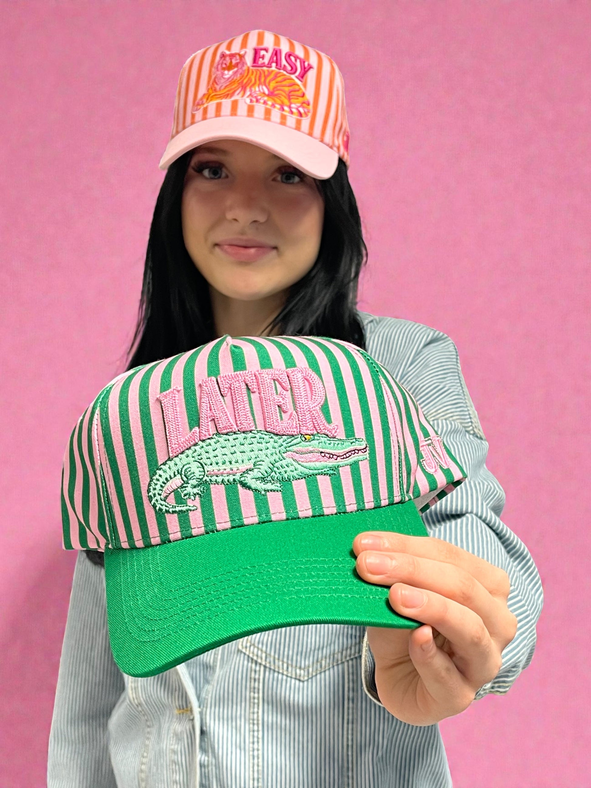 Person holding two colorful caps against a pink background