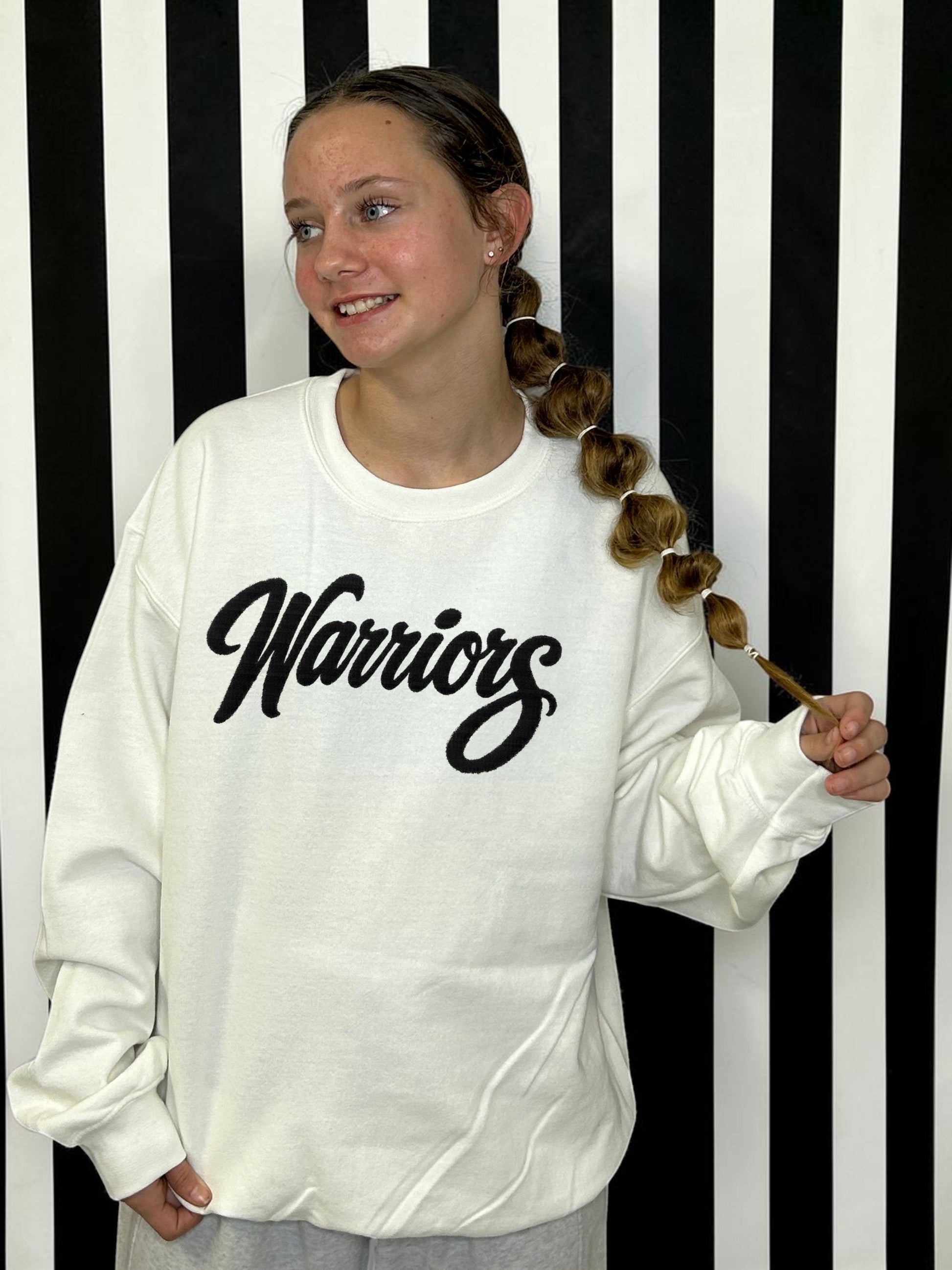 warriors' black fuzzy patch with white sweatshirt on a white and black striped background